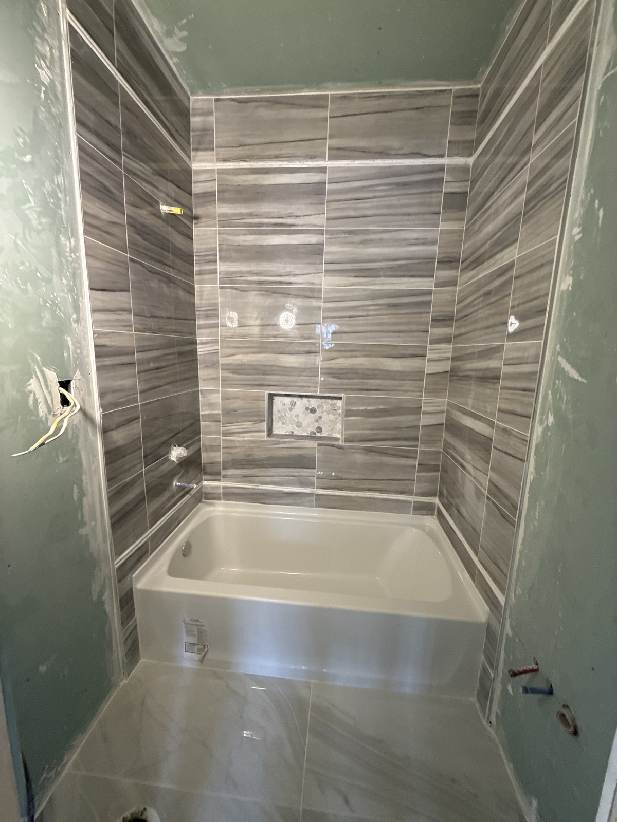 Tub surround tile install with pebble niche
